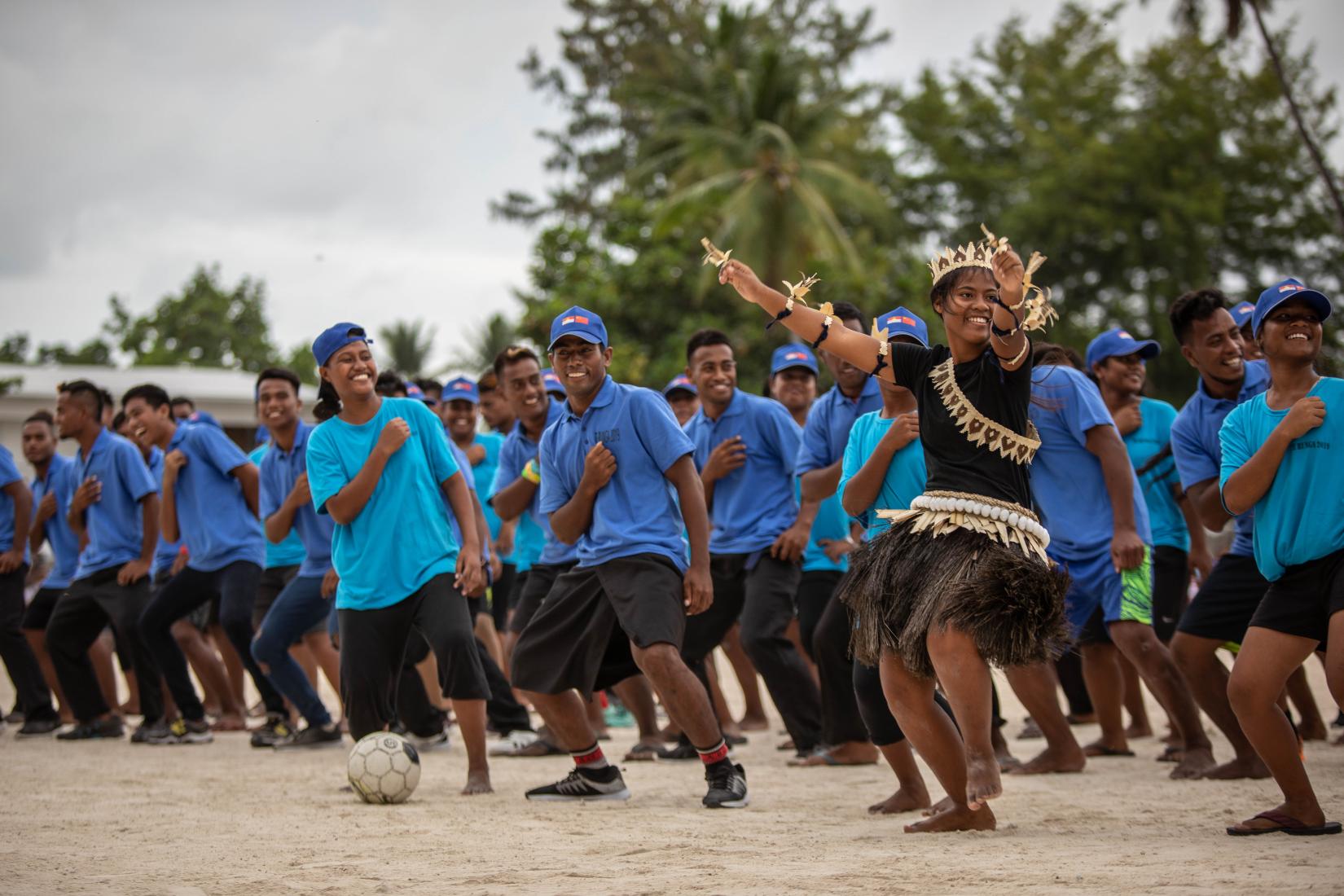 Kiribati. Young footballers dance with a girl in traditional dress at a UNFPA-supported tournament. Photo credit Carly Learson 